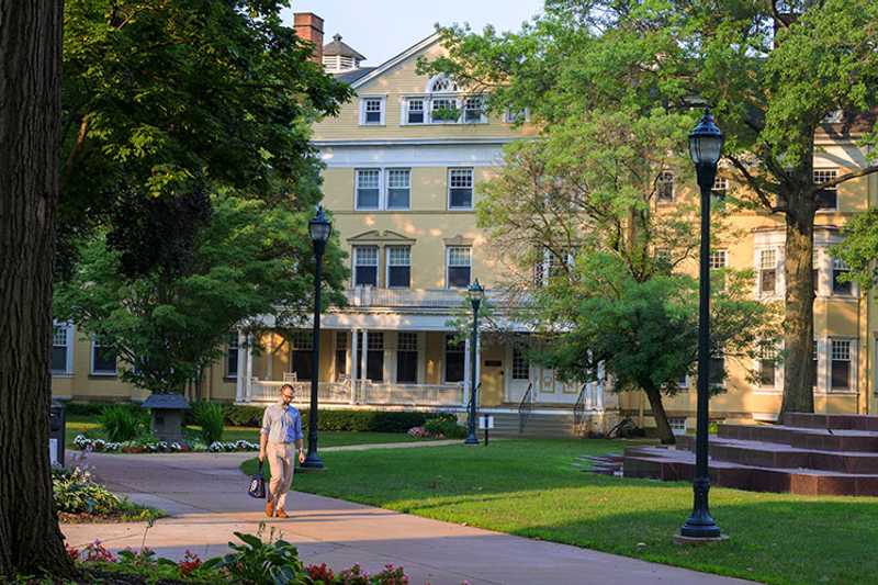 Photo of Guilford House on Mather Quad at Case Western Reserve University, with a student walking in front on sidewalk